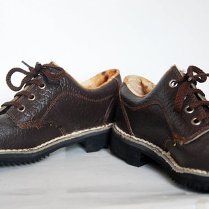 K&ouml;nnte beinhalten: Ein Paar braune Lederschn&uuml;rschuhe mit wei&szlig;en N&auml;hten um die Sohle.