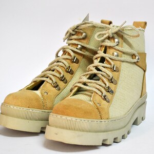 May include: A pair of beige canvas and suede hiking boots with brown laces and silver eyelets.