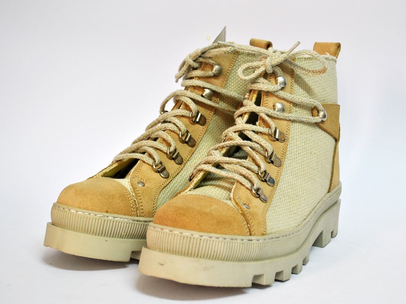 May include: A pair of beige canvas and suede hiking boots with brown laces and silver eyelets.