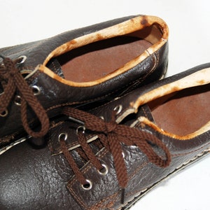 K&ouml;nnte beinhalten: Ein Paar braune Lederschn&uuml;rschuhe mit wei&szlig;en N&auml;hten an den R&auml;ndern. Die Schuhe haben braune Schn&uuml;rsenkel und sind abgenutzt.