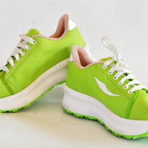 May include: A pair of bright green sneakers with white laces and a white platform sole. The sneakers have a white logo on the side.