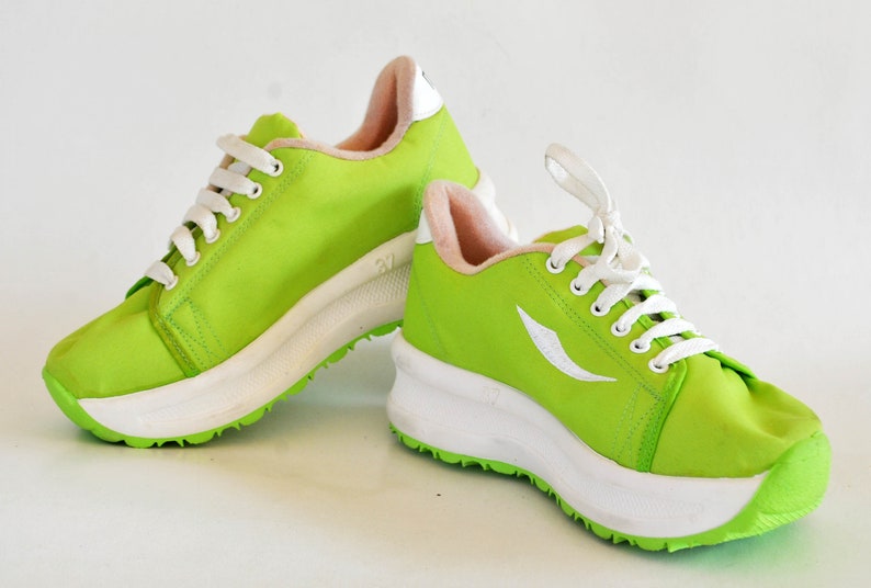 May include: A pair of bright green sneakers with white laces and a white platform sole. The sneakers have a white logo on the side.