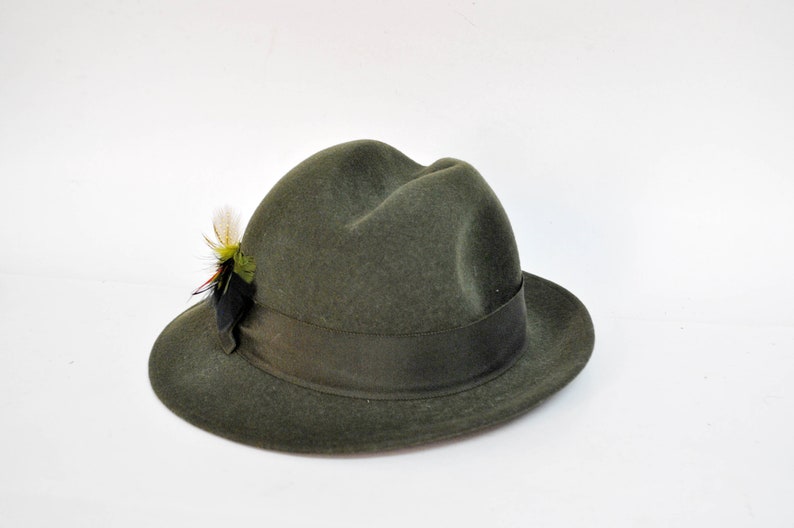 May include: A green felt fedora hat with a black and green feather accent.
