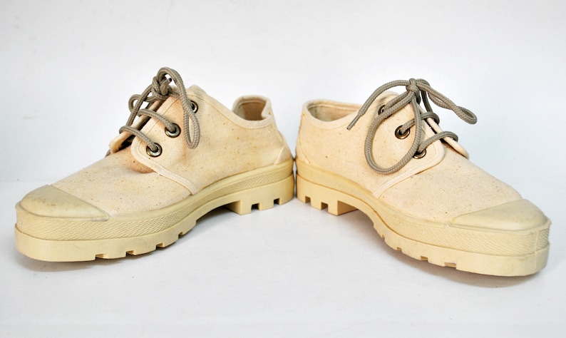 May include: A pair of off-white canvas shoes with thick, white rubber soles and brown laces.