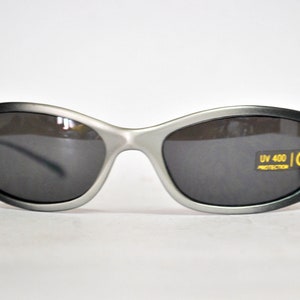 May include: Silver-framed sunglasses with dark gray lenses. The sunglasses have a UV 400 protection label and a CE mark.