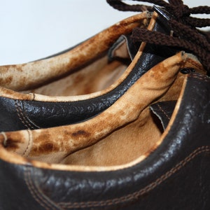 K&ouml;nnte beinhalten: Nahaufnahme eines Paares brauner Lederschuhe mit einem abgenutzten, braunen Innenfutter. Die Schuhe haben Schn&uuml;rsenkel und Metall&ouml;sen.