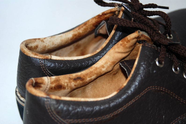 K&ouml;nnte beinhalten: Nahaufnahme eines Paares brauner Lederschuhe mit einem abgenutzten, braunen Innenfutter. Die Schuhe haben Schn&uuml;rsenkel und Metall&ouml;sen.