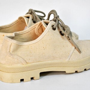 May include: A pair of off-white canvas shoes with thick, textured soles and laces. The shoes have a worn, vintage look.