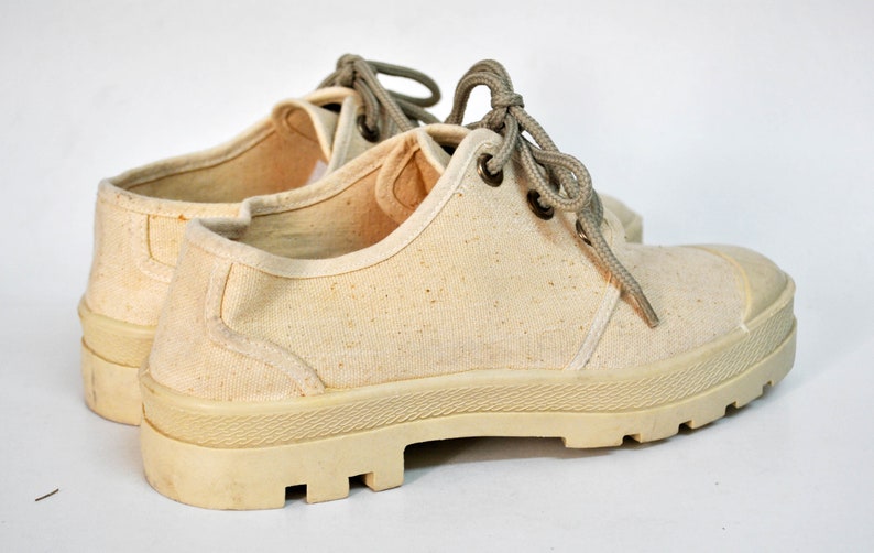 May include: A pair of off-white canvas shoes with thick, textured soles and laces. The shoes have a worn, vintage look.