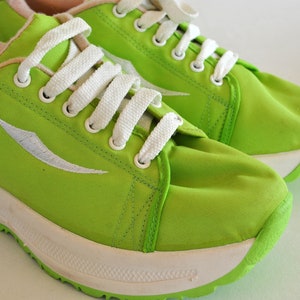 May include: A pair of lime green canvas sneakers with white laces and a white sole. The sneakers have a white logo on the side.