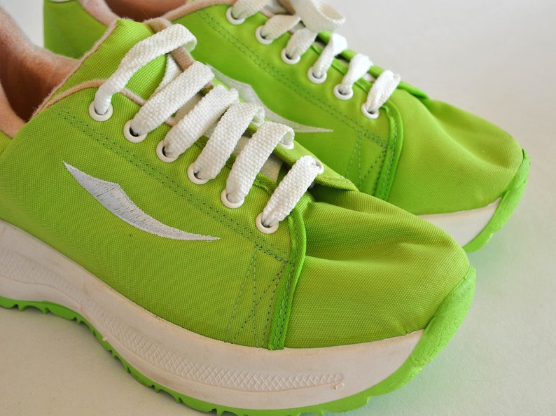 May include: A pair of lime green canvas sneakers with white laces and a white sole. The sneakers have a white logo on the side.