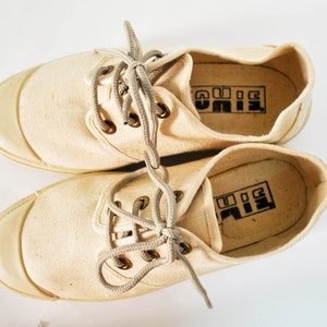 May include: A pair of off-white canvas shoes with white laces and a black "BIG" logo on the inside of each shoe.