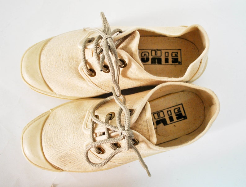 May include: A pair of off-white canvas shoes with white laces and a black "BIG" logo on the inside of each shoe.