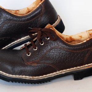 K&ouml;nnte beinhalten: Ein Paar braune Lederschuhe mit Schn&uuml;rsenkeln. Die Schuhe haben ein wei&szlig;es N&auml;htdetail um die Sohle und ein strukturiertes Leder-Obermaterial.