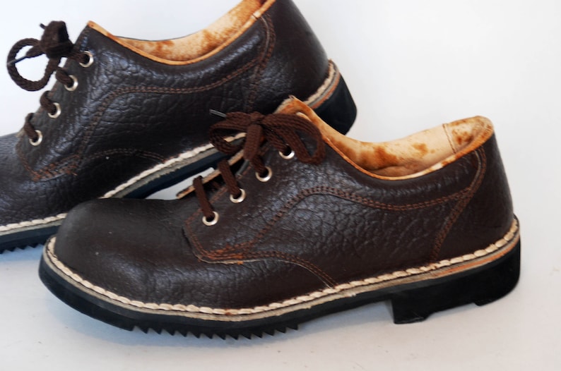 K&ouml;nnte beinhalten: Ein Paar braune Lederschuhe mit Schn&uuml;rsenkeln. Die Schuhe haben ein wei&szlig;es N&auml;htdetail um die Sohle und ein strukturiertes Leder-Obermaterial.