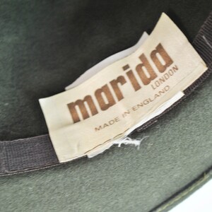 May include: A green felt fedora hat with a brown ribbon and a white label that reads "marida LONDON MADE IN ENGLAND".