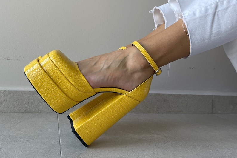 May include: Yellow platform heels with a crocodile-embossed leather upper and a thick platform sole.
