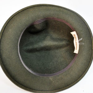 May include: A dark green felt fedora hat with a brown leather band and a label that reads "D'p-Jones".