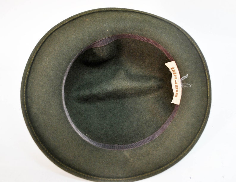 May include: A dark green felt fedora hat with a brown leather band and a label that reads "D'p-Jones".