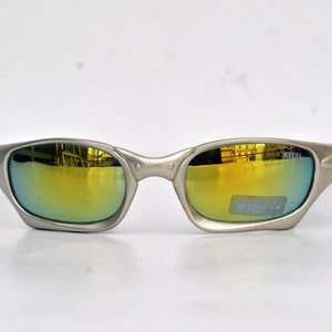 May include: Silver-toned sunglasses with a gold mirrored lens. The sunglasses have a Master CE label on the right lens.