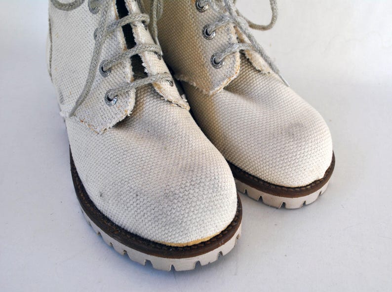 May include: A pair of white canvas high-top boots with brown laces and brown soles.