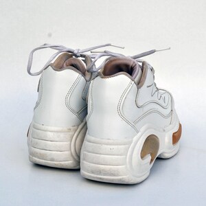 Puede incluir: Un par de zapatillas blancas de plataforma con suela gruesa y cierre de cordones.