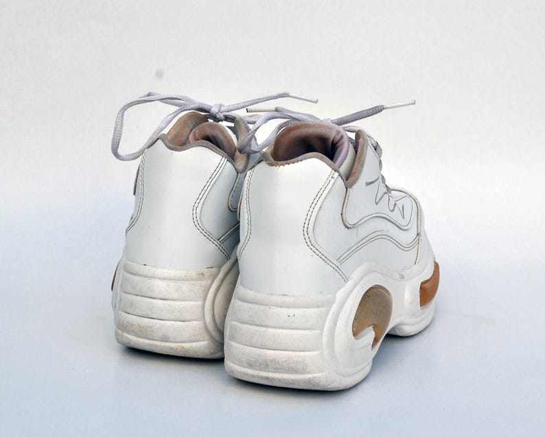 Puede incluir: Un par de zapatillas blancas de plataforma con suela gruesa y cierre de cordones.