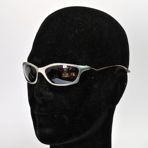 May include: A pair of silver-framed sunglasses with dark lenses. The sunglasses have a UV 400 and CE label on the lenses.