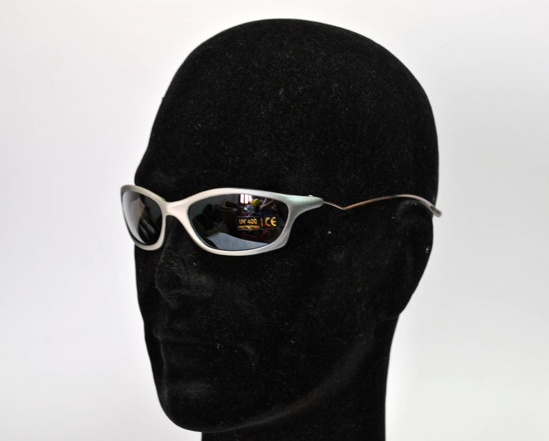 May include: A pair of silver-framed sunglasses with dark lenses. The sunglasses have a UV 400 and CE label on the lenses.