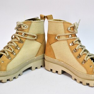 May include: A pair of beige canvas and suede hiking boots with a chunky white sole and laces.