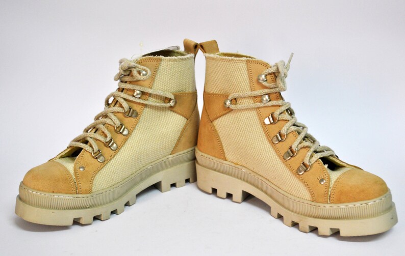 May include: A pair of beige canvas and suede hiking boots with a chunky white sole and laces.