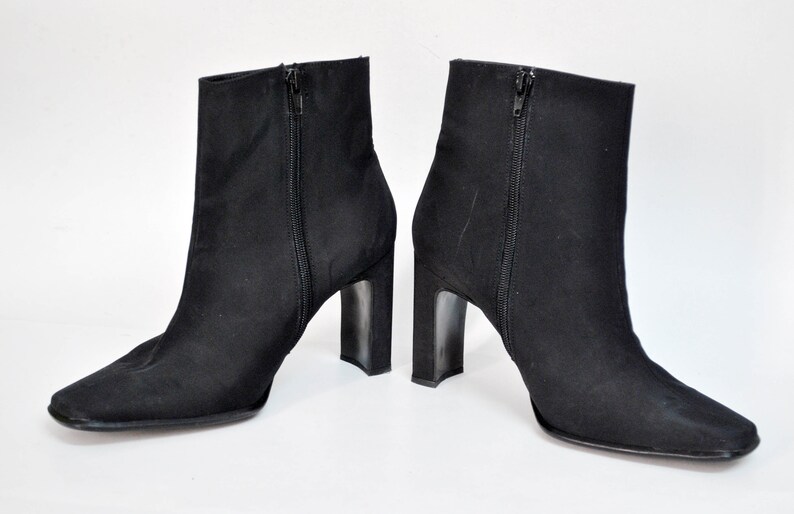 May include: A pair of black ankle boots with a square toe and a block heel.