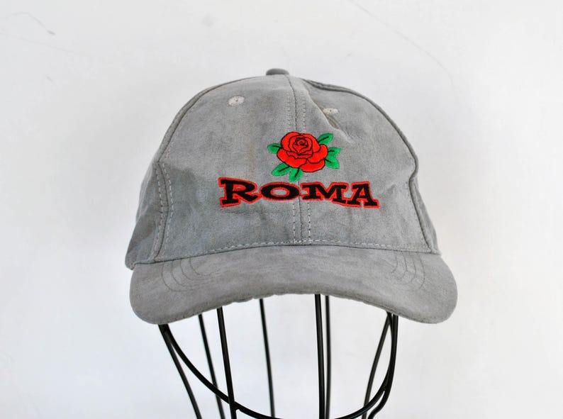 May include: A gray suede baseball cap with a red rose and the word "ROMA" embroidered in black and red.
