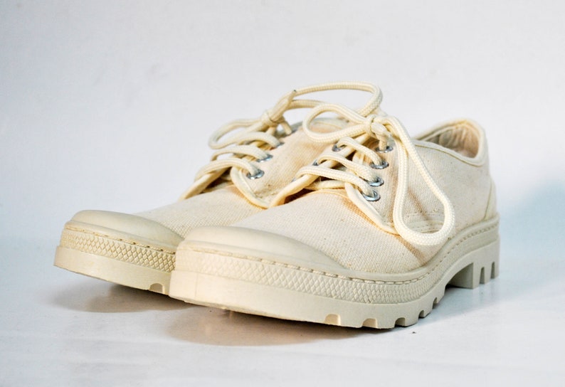 May include: A pair of off-white canvas low-top shoes with white laces and a thick white rubber sole.