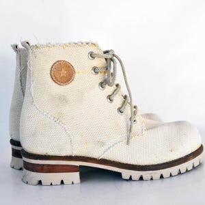 May include: White canvas high-top boots with brown leather accents and a white star logo.