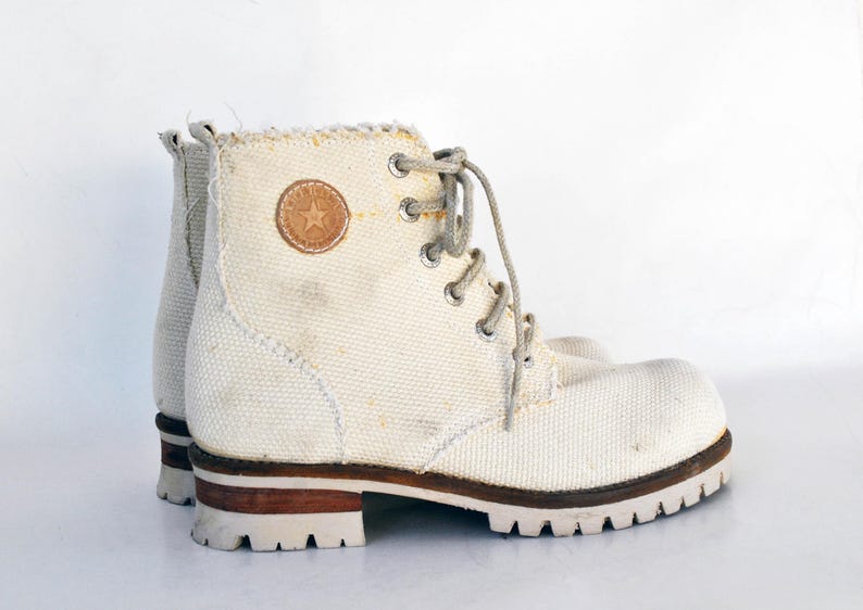 May include: White canvas high-top boots with brown leather accents and a white star logo.