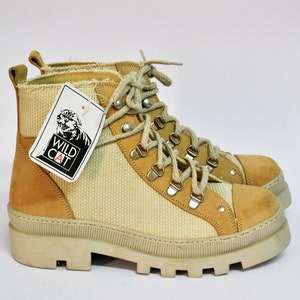 May include: Beige and brown hiking boots with a white rubber sole. The boots have a lace-up closure and a tag that says "Wild Cat".