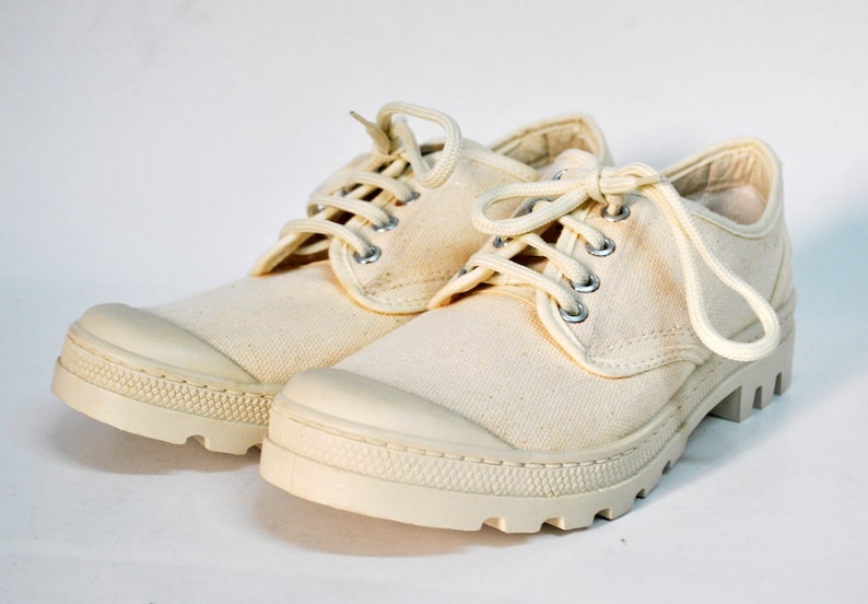 May include: A pair of off-white canvas low-top shoes with white laces. The shoes have a thick, white rubber sole.