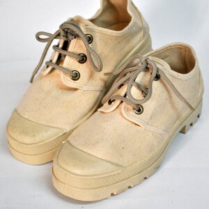 May include: A pair of off-white canvas shoes with thick white soles and brown laces.
