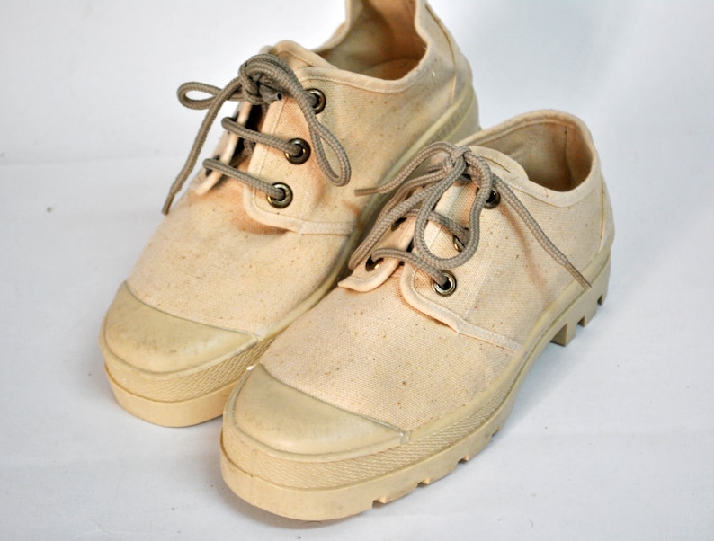 May include: A pair of off-white canvas shoes with thick white soles and brown laces.