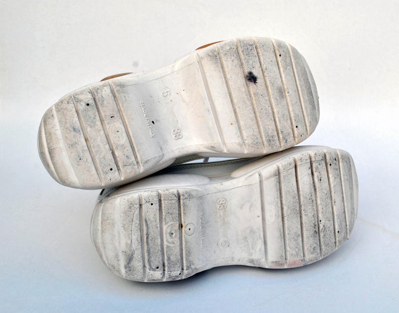 Puede incluir: Un par de zapatillas blancas de plataforma con suela texturizada. Las suelas est&aacute;n marcadas con la talla 38 y "Made in Italy".