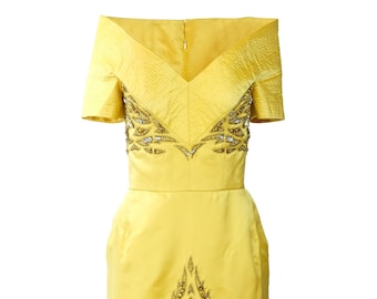 May include: A bright yellow, knee-length dress with an off-the-shoulder neckline. The dress features intricate beadwork in gold and silver tones along the bodice and skirt. The dress has short sleeves and a fitted waist, creating a classic silhouette.