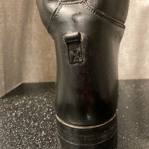 May include: Black leather riding boots with a zipper on the back of the boot.