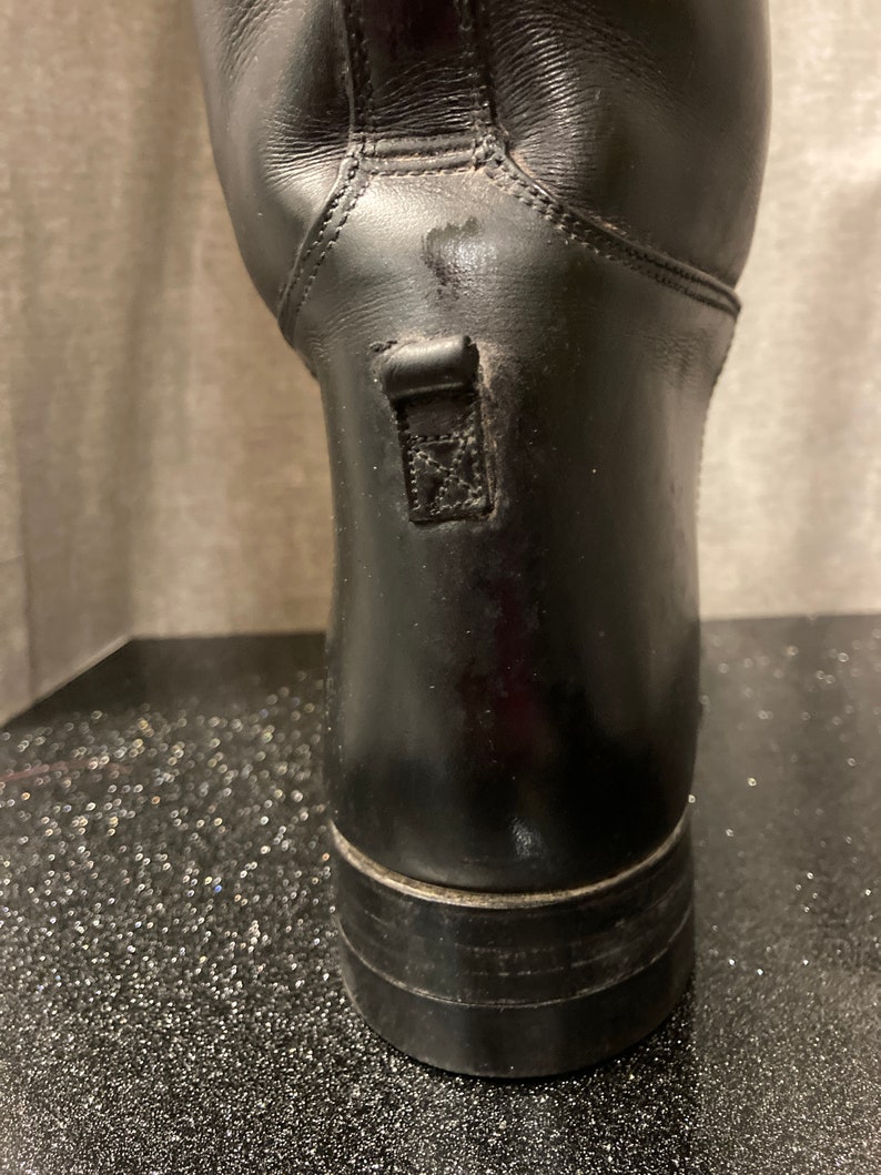 May include: Black leather riding boots with a zipper on the back of the boot.