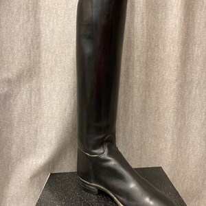May include: A pair of black leather riding boots with a pointed toe and a tall shaft.