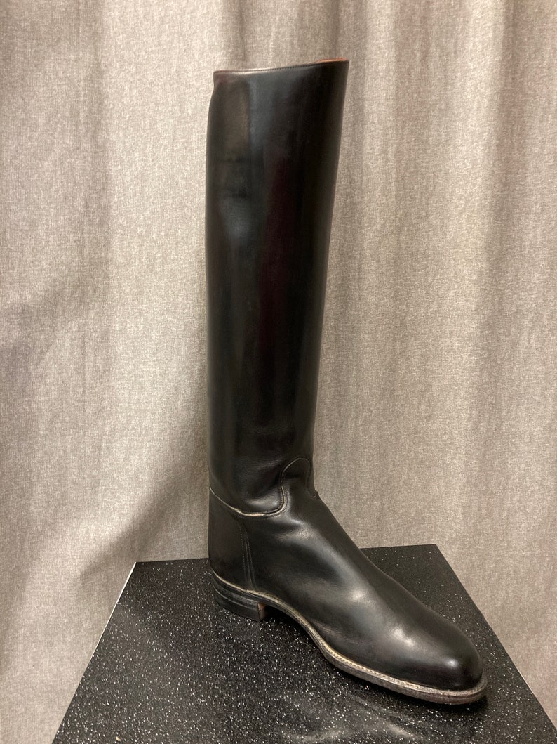 May include: A pair of black leather riding boots with a pointed toe and a tall shaft.