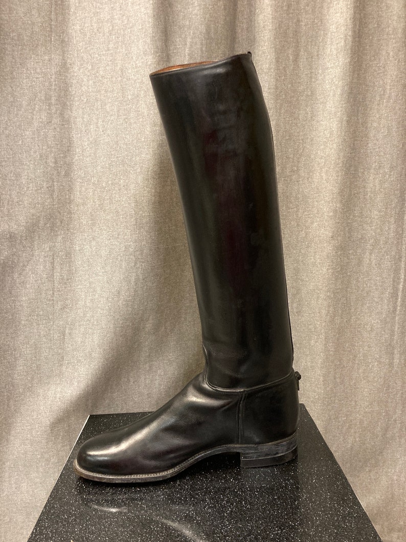 May include: Black leather riding boots with a tall shaft and a pointed toe.