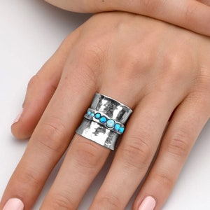 a woman's hand with a silver ring with turquoise stones