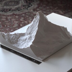 Puede incluir: Un modelo 3D impreso en blanco de una cordillera. El modelo es detallado y realista, con picos y valles agudos.
