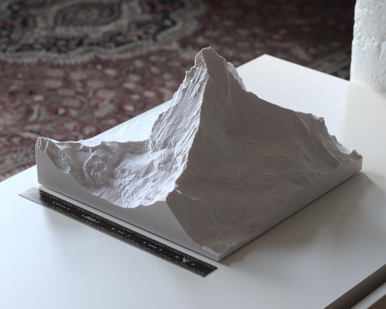 Puede incluir: Un modelo 3D impreso en blanco de una cordillera. El modelo es detallado y realista, con picos y valles agudos.